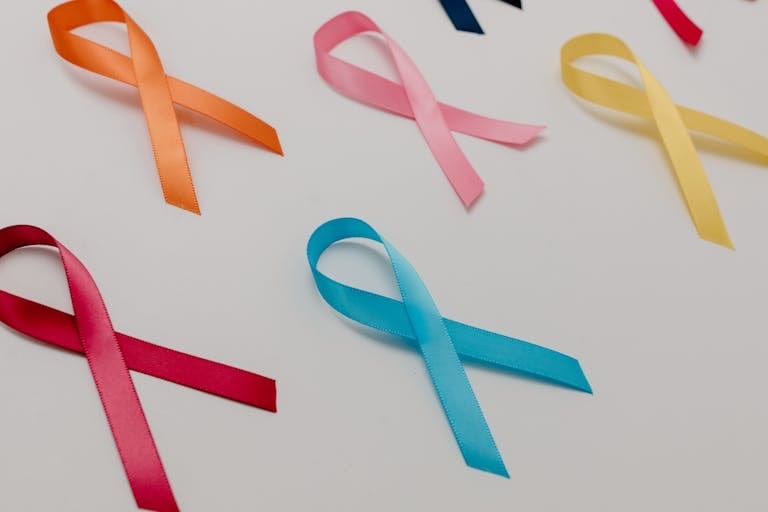 Various colored ribbons representing different cancer awareness causes on a white surface.
