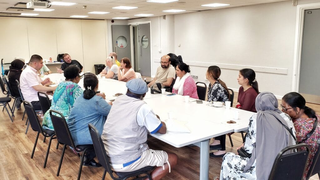 A group of individuals with sight impairment, seated around a table, engaged in discussions.