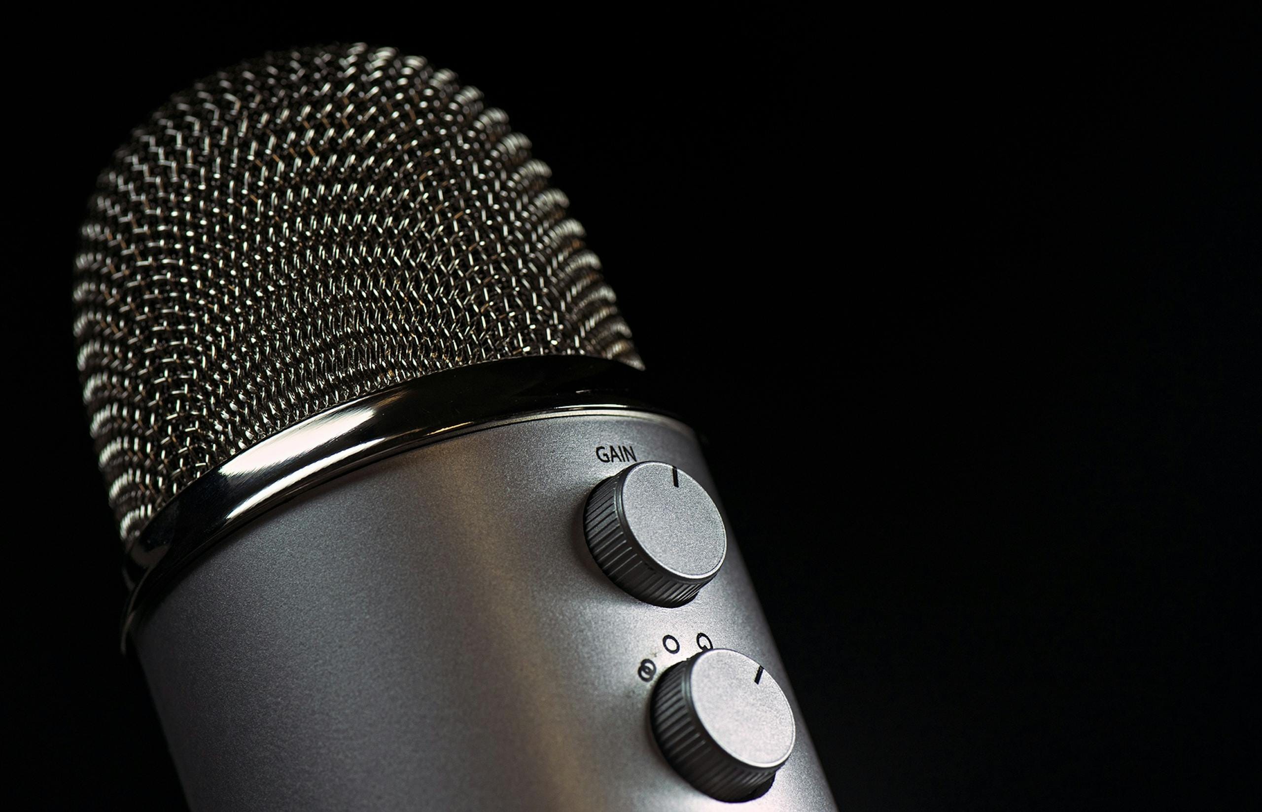 Photo by Pixabay Detailed close-up of a silver mesh microphone with gain control knobs against a dark background.