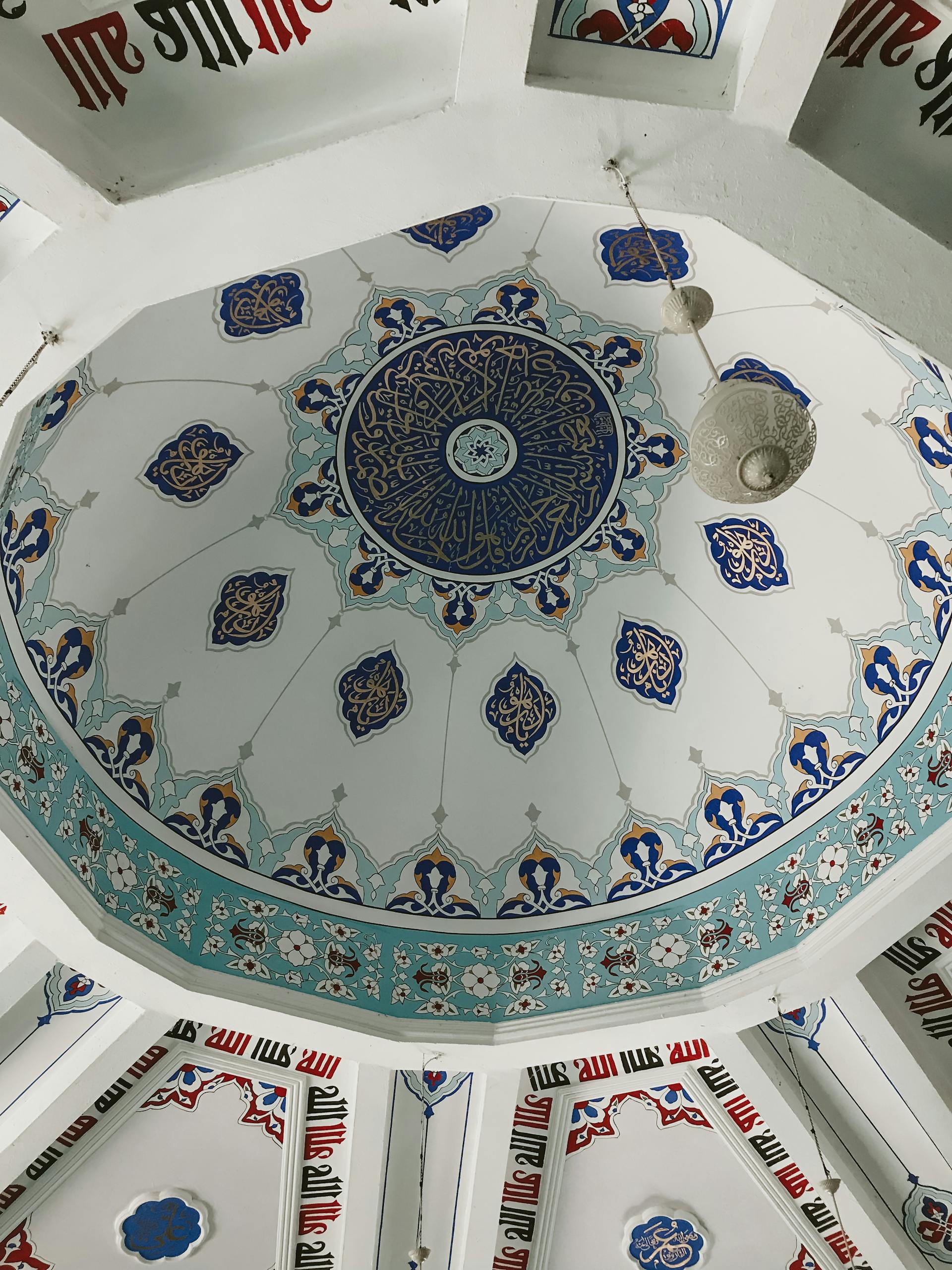 Stunning low angle view of a decorated dome ceiling in a mosque, showcasing Islamic art.